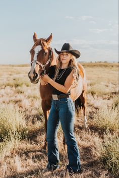 a woman standing next to a brown horse on top of a dry grass covered field