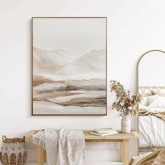 a white room with a bed and a painting on the wall next to a table