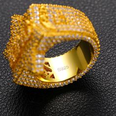 a gold ring with white and yellow diamonds on it's side, sitting on a black surface