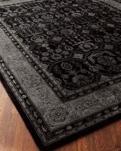 a large black rug on top of a wooden floor