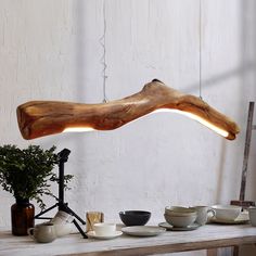 a wooden table topped with cups and saucers next to a lamp that is shaped like a fish