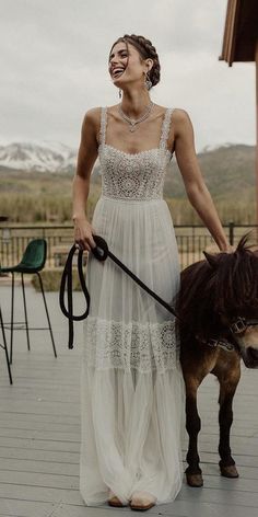 a woman in a white dress walking a horse