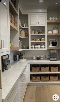 a kitchen with lots of white cabinets and drawers on the wall, along with baskets