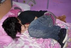 a woman laying on top of a bed next to a teddy bear