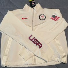 a white jacket with usps patches on the sleeves and back, sitting on a bed