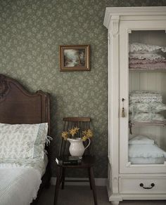 a bedroom with green wallpaper and white furniture