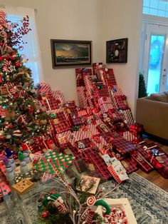 a christmas tree is covered with presents and wrapped in red and green plaid ribbon, surrounded by other holiday decorations