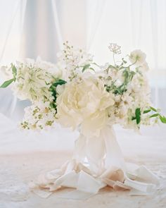 a vase filled with white flowers on top of a bed