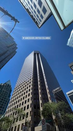 looking up at tall buildings in the city with blue sky and sun shining on them