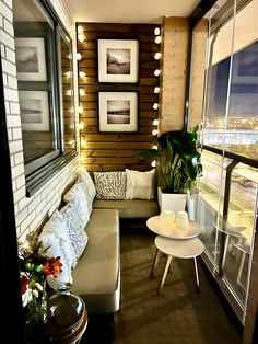 a living room filled with furniture next to a large window covered in string lights and potted plants