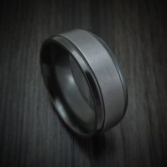 a wedding band with black ceramic inlays on a dark wood background, close up