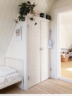 an attic bedroom with white walls and wooden floors