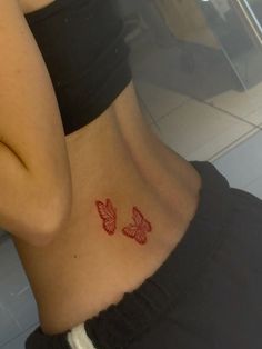 a woman's stomach with two red butterflies on her lower body and behind her is a mirror