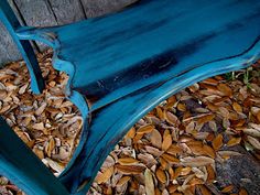 a blue bench sitting on top of a pile of leaves