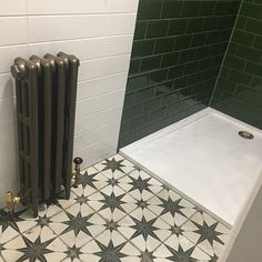 a bathroom with black and white tiles on the floor next to a radiator