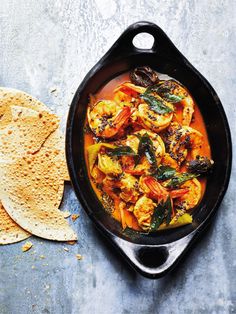 a skillet filled with shrimp and tortillas next to some tortilla chips