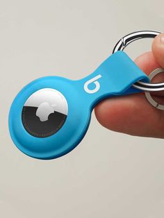 a hand holding a blue keychain with the number six on it's side