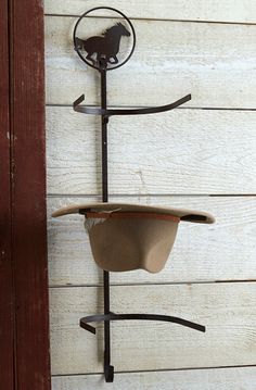 a hat hanging on the side of a wall with a wind chime attached to it