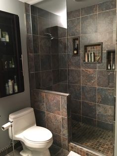 a bathroom with a walk in shower next to a white toilet and tiled flooring