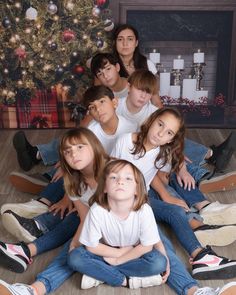 a group of children sitting in front of a christmas tree