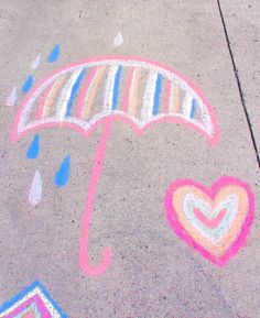 an umbrella and hearts drawn on the sidewalk with chalk pastel markers in front of it