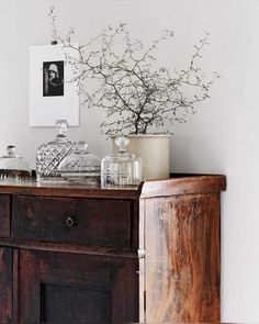 a wooden dresser topped with lots of glassware and a vase filled with flowers on top of it