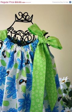 a dress with green and blue flowers on the bottom, tied to a hanger