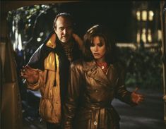 a man and woman standing next to each other in front of a building at night