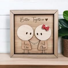 a wooden frame with two people holding hands and the words better together are in front of a potted plant