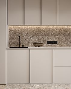 a kitchen with white cabinets and marble counter tops