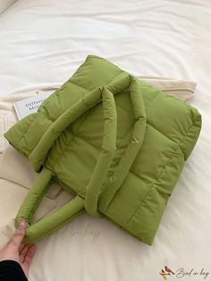 a person is laying down on a bed with a green jacket over their head and hand