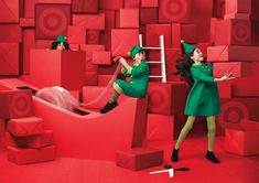 two women in green dresses and hats are standing on red cubes with ladders