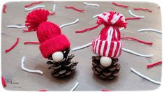 two knitted pine cones sitting next to each other on a wooden table with red and white decorations