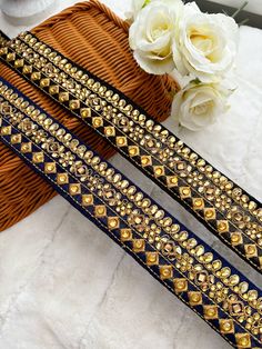 two pieces of blue and gold beaded leather with flowers on the table next to it