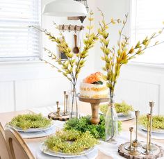 a table topped with plates covered in cake next to tall vases filled with flowers