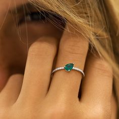 a close up of a person's hand with a ring on their finger and an emerald stone in the middle