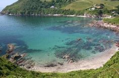 the water is crystal blue and clear with green hills in the background