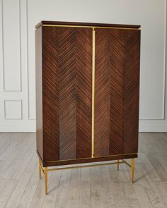 a wooden cabinet with gold trim and an arrow pattern on the front, against a white wall