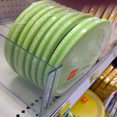 green plates are stacked on the shelf in a grocery store, ready to be sold