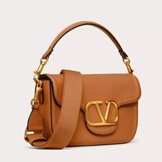 Expertly crafted from soft grainy calfskin leather, the Valentino Garavani Alltime shoulder bag exudes elegance and sophistication. Its versatile design allows you to wear it on your shoulder, cross-body or handheld, offering convenience and style in one. Complete with a metallic VLogo Signature detail, this bag is a must-have for any fashion-forward individual. Luxury Baguette Bag With Branded Hardware For Daily Use, Luxury Calf Leather Satchel Flap Bag, Elegant Calf Leather Shoulder Bag With Branded Hardware, Formal Brown Baguette Bag With Branded Hardware, Luxury Calf Leather Rectangular Shoulder Bag, Luxury Everyday Calf Leather Shoulder Bag, High-end Calf Leather Satchel Shoulder Bag, High-end Everyday Luxury Crossbody Shoulder Bag, Designer Leather Baguette Bag With Branded Hardware