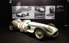 an old race car is on display in a museum exhibit with black and white photos