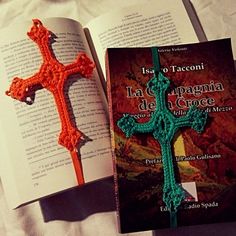 an open book with a crocheted cross on it sitting next to another book