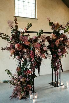 an arrangement of flowers and candles are arranged on the floor in front of a window