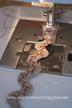 the sewing machine is being sewn with red thread on it's side,