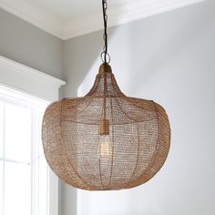 a light fixture hanging from the ceiling in a room with white walls and wood flooring