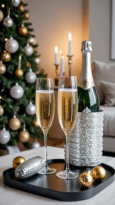 two glasses of champagne on a tray next to a christmas tree