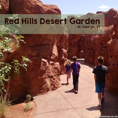 two people walking down a path between red hills desert garden and st george's park