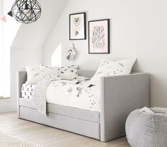 a bedroom with white walls and flooring has a gray daybed in the corner