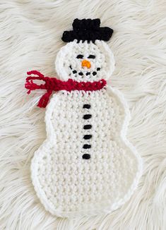 a crocheted snowman ornament laying on a white furnishing