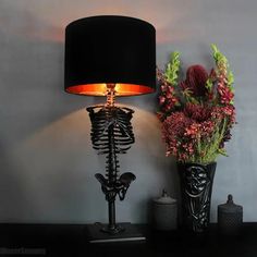 a lamp that is on top of a table next to a vase with flowers in it